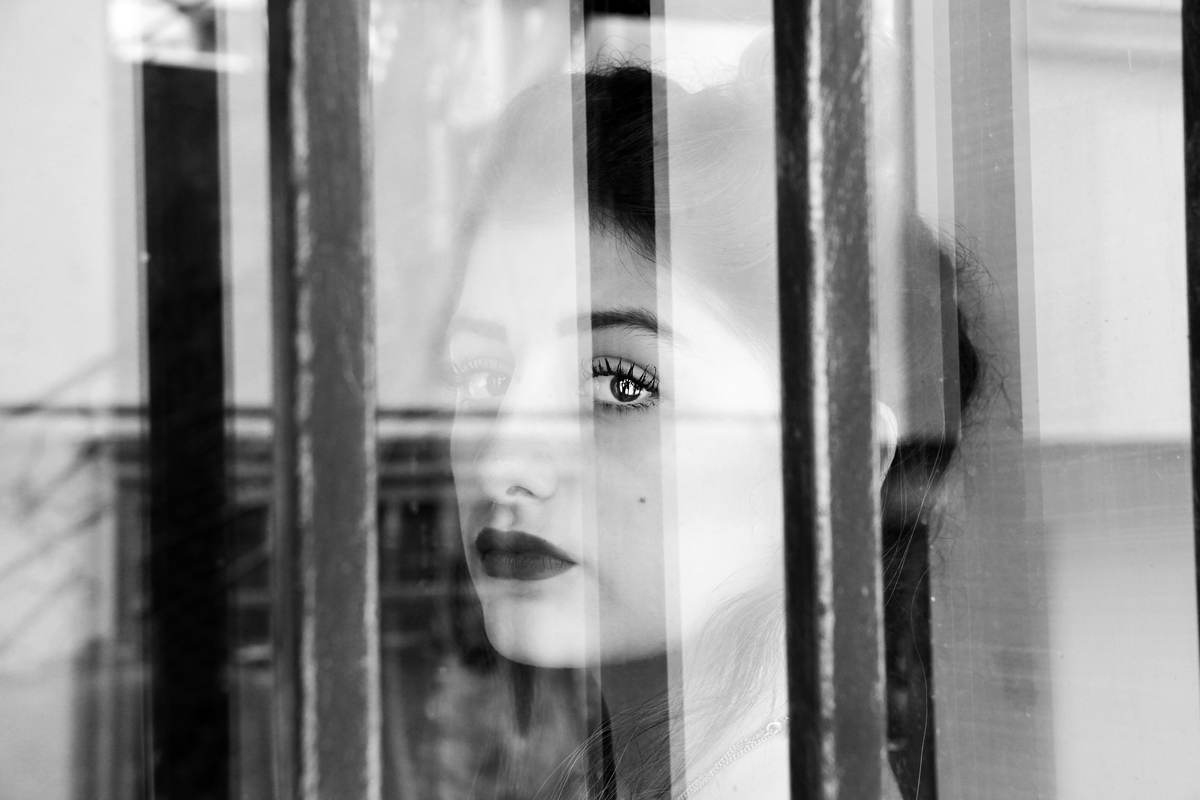 Woman looking through glass bars — searching for clarity
