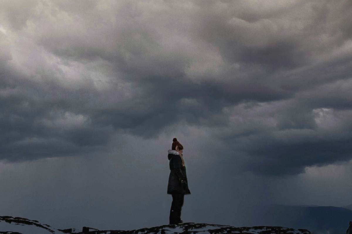 Woman standing under a storm sky — midlife's perfect storm