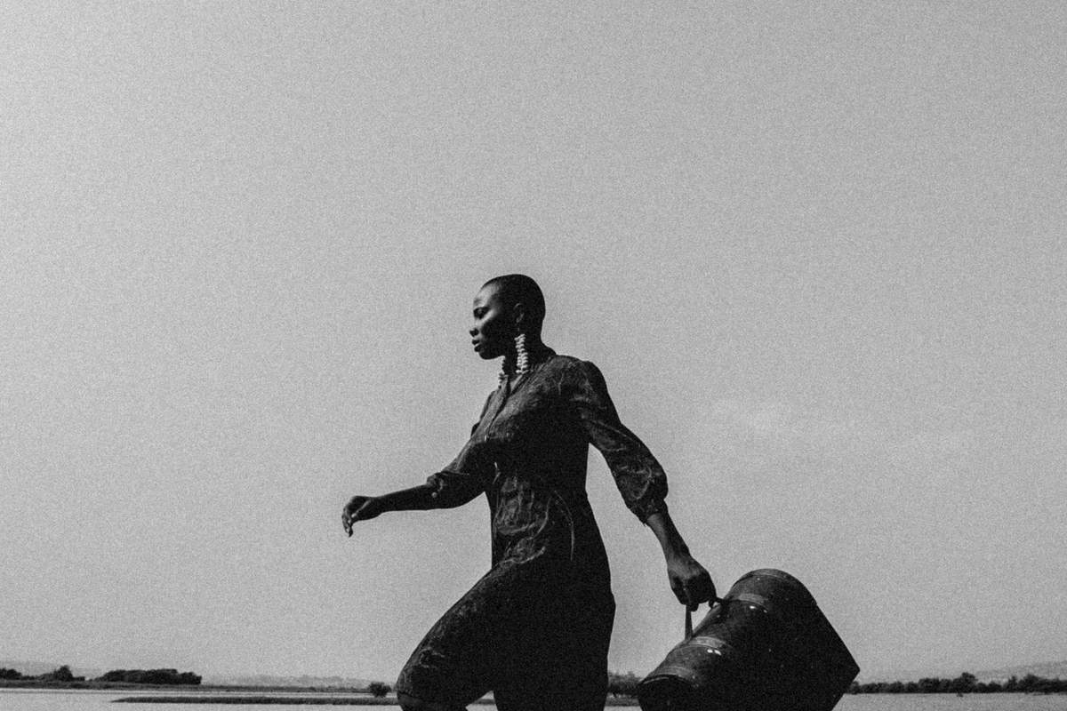 Woman walking with luggage by the water — starting over in your 40s